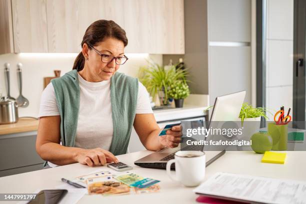 mujer concentrada calculando los gastos del hogar - evento mensual fotografías e imágenes de stock