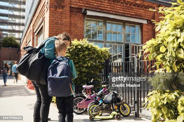 woman standing with son at school gate on sunny day - school scandinavia stock pictures, royalty-free photos & images