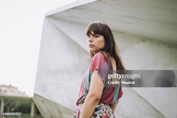 portrait of young woman looking back over shoulder - über die schulter blicken stock-fotos und bilder