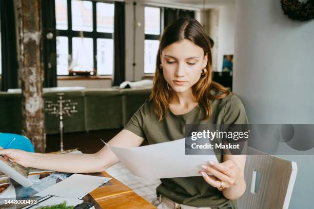 concentrated female food stylist holding photograph while working in studio - vergleich stock-fotos und bilder