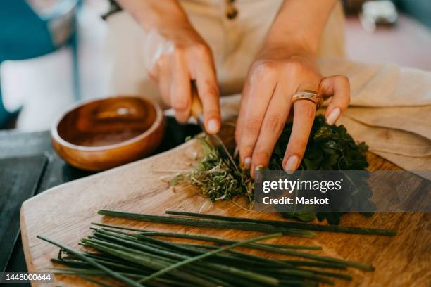 hands of female chef chopping leafy vegetable on cutting board in studio - chopping 個照片及圖片檔