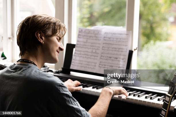 passionate young man playing piano at home - practicing piano stock pictures, royalty-free photos & images