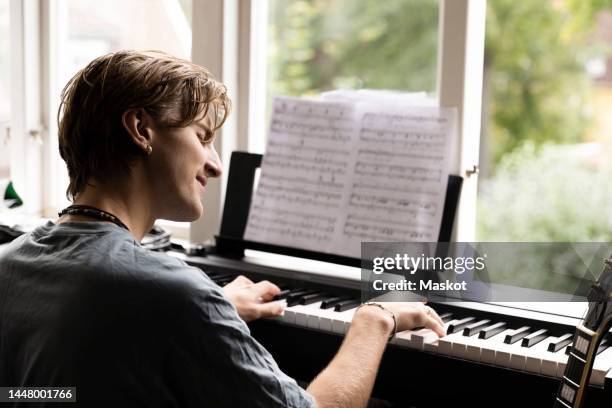 passionate young man playing piano at home - piano bildbanksfoton och bilder