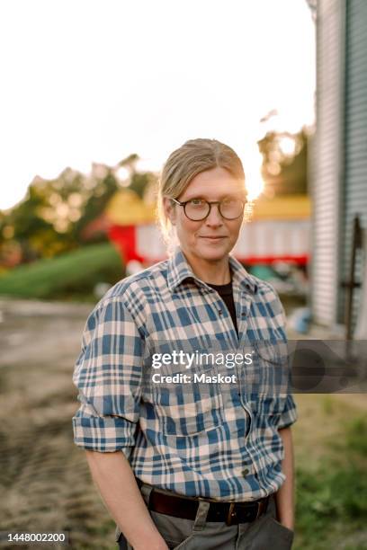 smiling female farmer with hands in pockets standing at field - dairy factory worker stock pictures, royalty-free photos & images