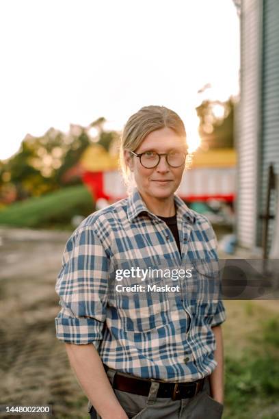 smiling female farmer with hands in pockets standing at field - farmhouse stock pictures, royalty-free photos & images