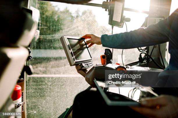 hand of farmer operating computer sitting in tractor on sunny day - digital agriculture stock pictures, royalty-free photos & images