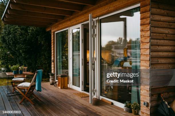 wooden porch with chairs by glass door outside house - porch stock pictures, royalty-free photos & images