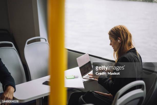 female entrepreneur typing on laptop while sitting in ferry - commuter ferry stock pictures, royalty-free photos & images