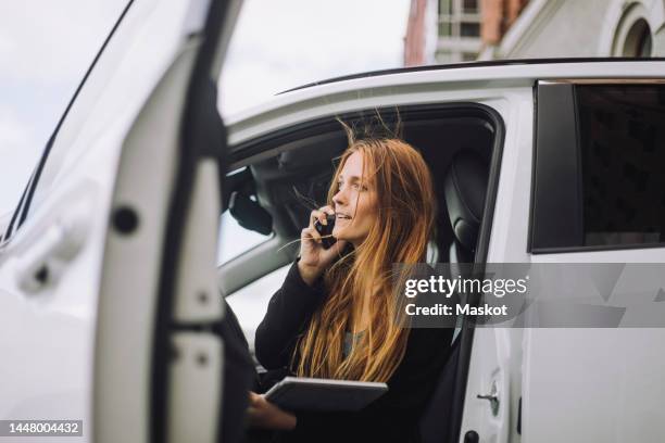 businesswoman talking on smart phone while disembarking from car - car scandinavia stock pictures, royalty-free photos & images