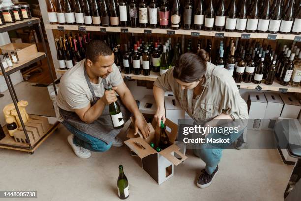 male and female business owners removing bottles from box at wine store - tablet alcohol stock-fotos und bilder