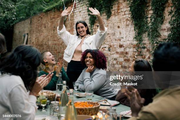 smiling woman gesturing while enjoying with friends during dinner party in back yard - garden party stock-fotos und bilder