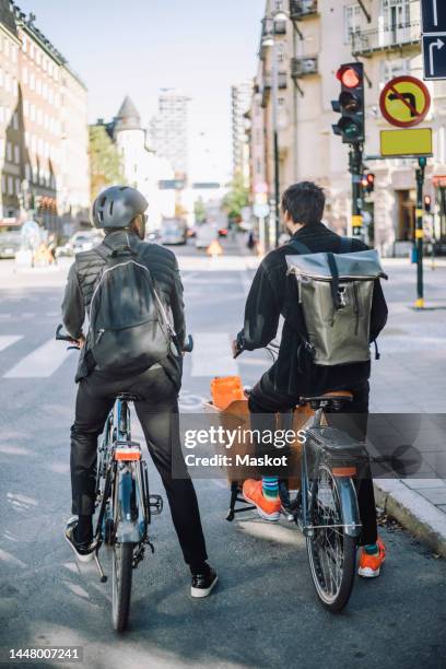 businessmen with cargo bike and bicycle waiting at traffic signal on road - road signal stock pictures, royalty-free photos & images