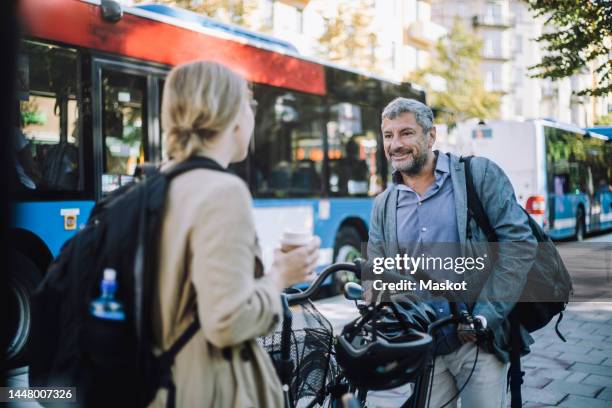 male and female business colleagues with bicycles talking to each other at street - sustainable transportation stock pictures, royalty-free photos & images