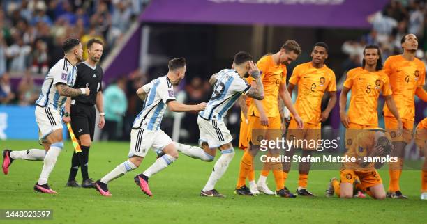 Nicolas Otamendi of Argentina and Nicolas Tagliafico of Argentina celebrate after their sides victory Netherlands players look dejected after their...