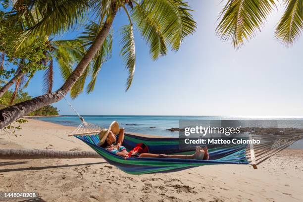 woman with headphones lying on a hammock at the beach, fiji - fiji stock-fotos und bilder