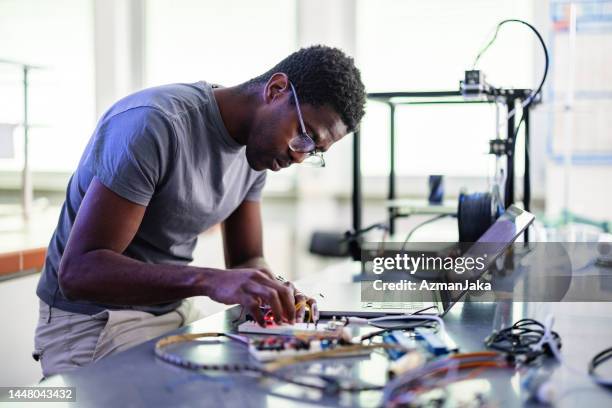 african-american technician repairing a 3d printer in laboratory - prototype stock pictures, royalty-free photos & images