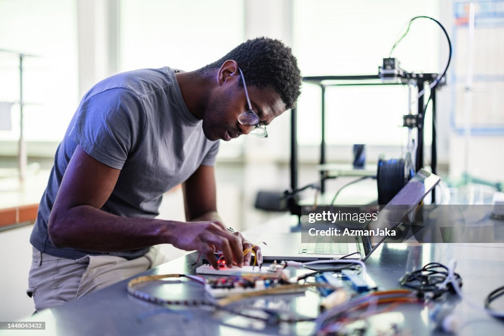 Técnico afro-americano reparando uma impressora 3D em laboratório