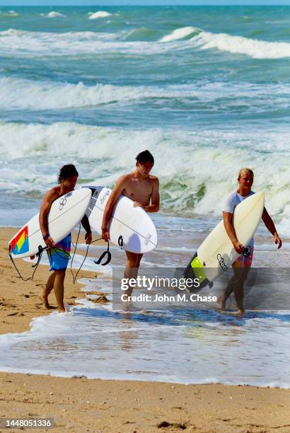 surfers walk along the beach, new smyrna beach, florida (usa) - chase atlantic stock-fotos und bilder