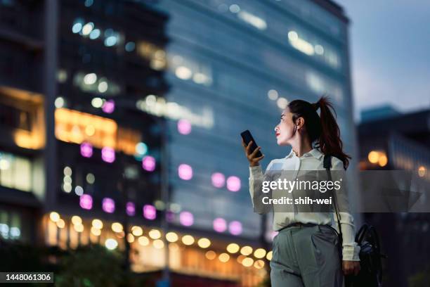 jeune femme d’affaires utilisant un smartphone dans le quartier financier, - téléphone équipement de télécommunication photos et images de collection