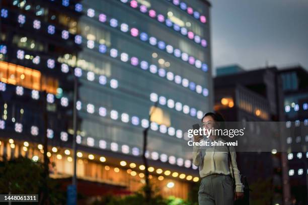 young businesswoman using smartphone in financial district, - taiwan night market stock pictures, royalty-free photos & images