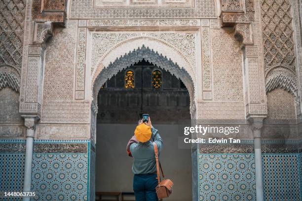 asiatische chinesische touristin fotografiert und bewundert die fez-moschee bou inania madressa - fez stock-fotos und bilder