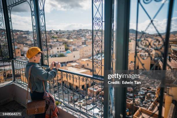 asian chinese female tourist photographing at rooftop chouwara leather traditional tannery in ancient medina of fes el bali, morocco, africa. - fez morocco stock pictures, royalty-free photos & images