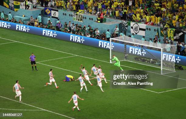 Croatia players celebrate after the team's victory in the penalty shoot out as Marquinhos of Brazil reacts to missing his penalty during the FIFA...