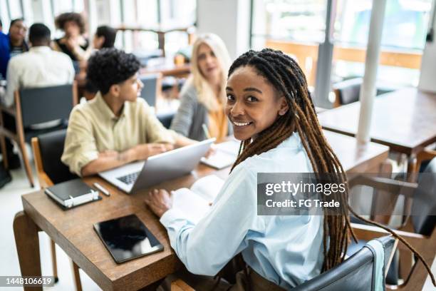 portrait of a young woman studying with friends in a library - independent school stock pictures, royalty-free photos & images