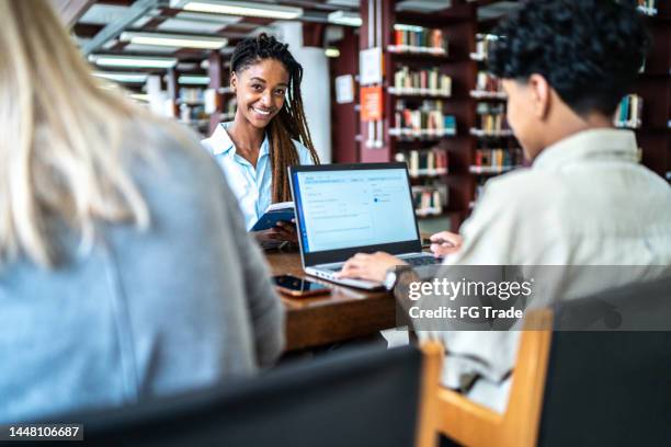 porträt einer jungen frau, die mit freunden in einer bibliothek lernt - öffentliche bibliothek stock-fotos und bilder