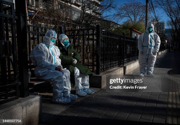 Epidemic control workers wear protective equipment to protect against the spread of COVID-19 as they take a break from work cleaning an area that was...