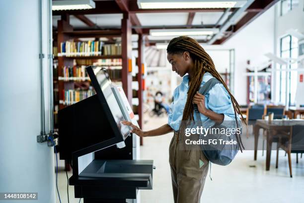 student sucht ein buch im bibliothekssystem - selbstbedienung stock-fotos und bilder