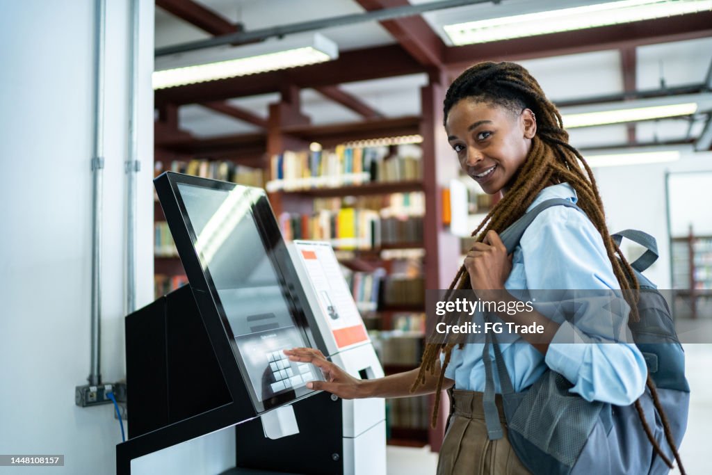 Retrato de un estudiante buscando un libro en el sistema de bibliotecas