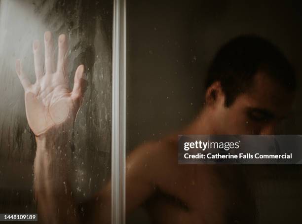 a man pushes his hand against a glass shower door - hombre en la ducha fotografías e imágenes de stock