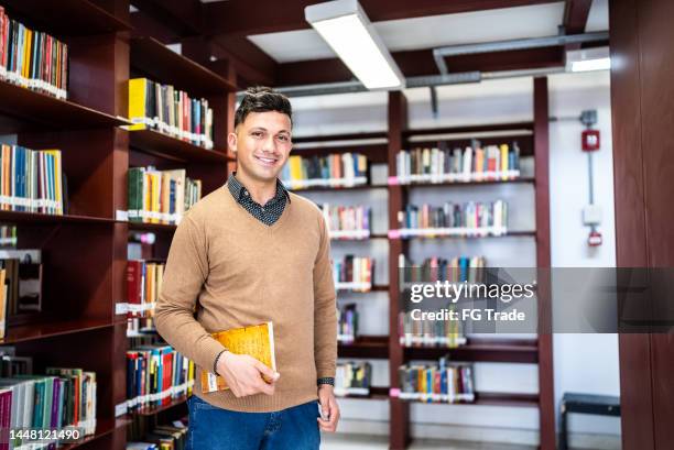 Portrait Of A Young Man Holding A Book In A Library Photos and Premium ...