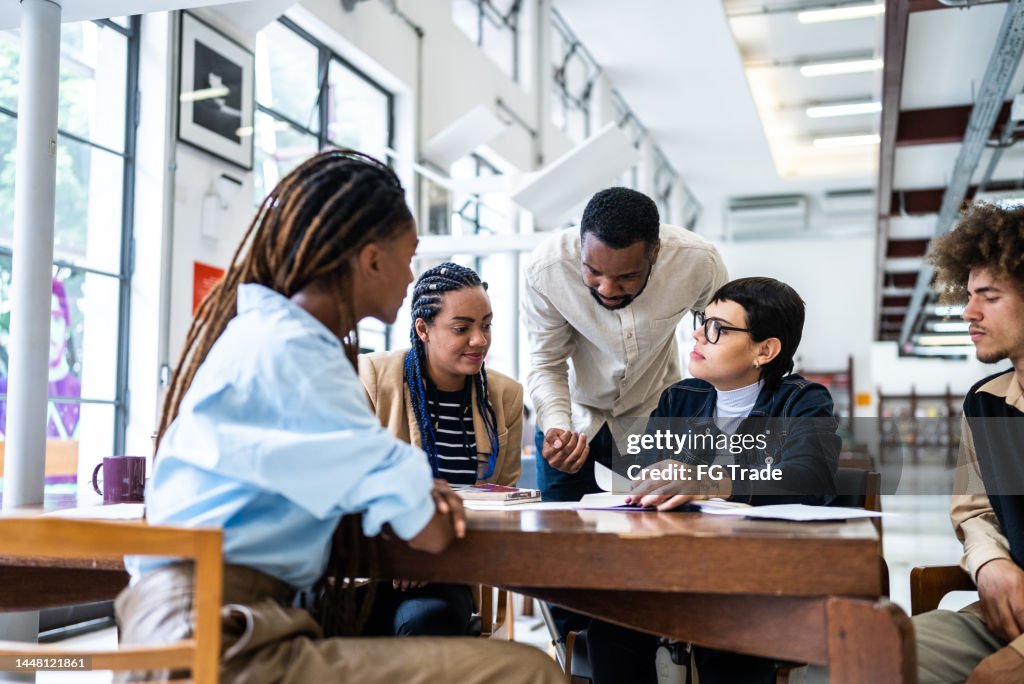 Professor ajudando os alunos na biblioteca - incluindo mulher transgênero