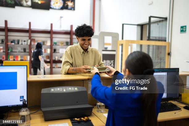 giovane donna che prende in prestito un libro dalla biblioteca - bibliotecario foto e immagini stock