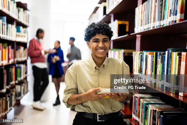 porträt einer jungen frau, die in der bibliothek ein buch liest - self improvement stock-fotos und bilder