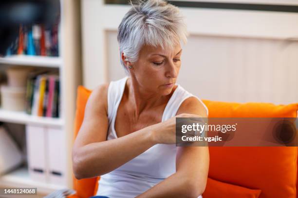 mature woman applies transdermal patch - hrt pill stockfoto's en -beelden