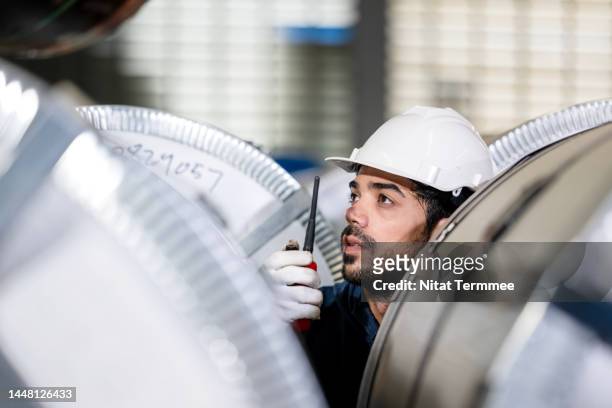 stainless steel coil and metal sheet industrial. overhead crane operator talking on a walkies talkies with his team at steel coils rolled warehouse in a steel factory. - iron roll stockfoto's en -beelden