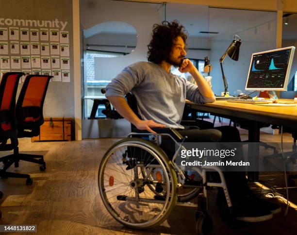 male worker in wheelchair concentrating in office - office stretches stock pictures, royalty-free photos & images