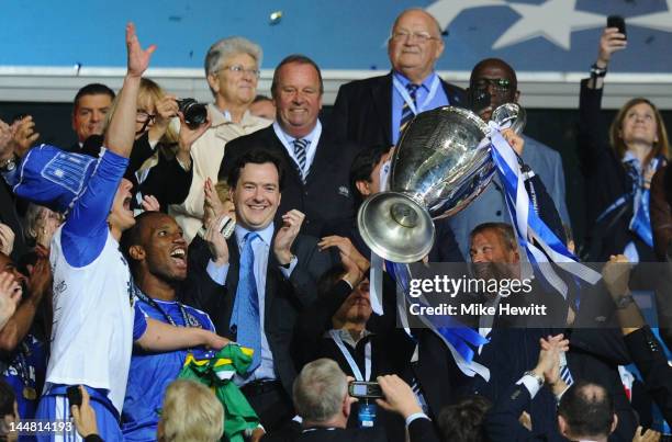 Club owner Roman Abramovich lifts the trophy in celebration while Chancellor of the Exchequer George Osborne applauds after their victory in the UEFA...