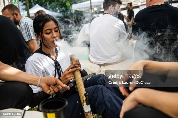 People smoke marijuana from a bong at the Thai High Convention on December 10, 2022 in Chiang Mai, Thailand. The Thai High Club hosts its first...