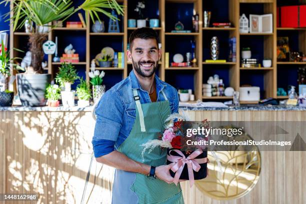 a handsome man is holding flowers in a modern flower store. - global gift stock pictures, royalty-free photos & images