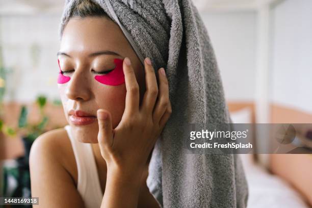 a portrait of a happy beautiful woman using eye patches while keeping her eyes closed - human finger stock pictures, royalty-free photos & images