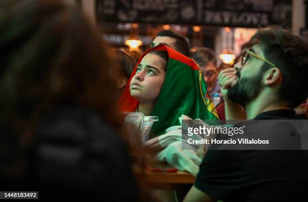Portuguese supporter, covering her head with the national flag, reacts while watching onscreen the 2022 World Cup Quarter-Finals Morocco-Portugal in...