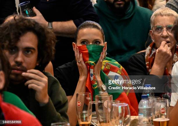 Portuguese supporter covers her face with the national flag while watching onscreen the 2022 World Cup Quarter-Finals Morocco-Portugal in Time Out...