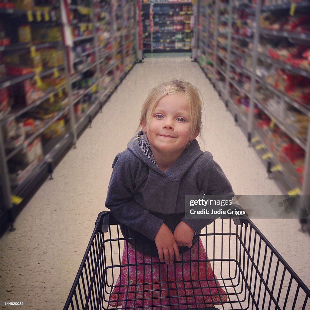 Girl standing on end of shopping trolley
