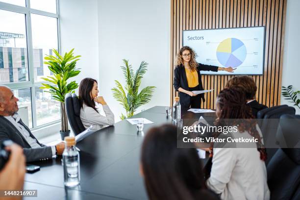 empresaria liderando reunión de negocios utilizando gráfico de estadísticas en presentación tv - presentación fotografías e imágenes de stock