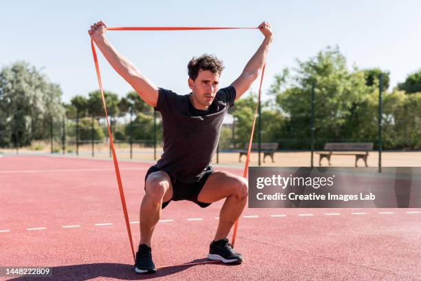 athletic man exercising with an elastic band - gummiband stock-fotos und bilder