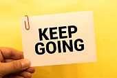 On a light pink background - a craft envelope. It has a white sheet of paper that says KEEP GOING.